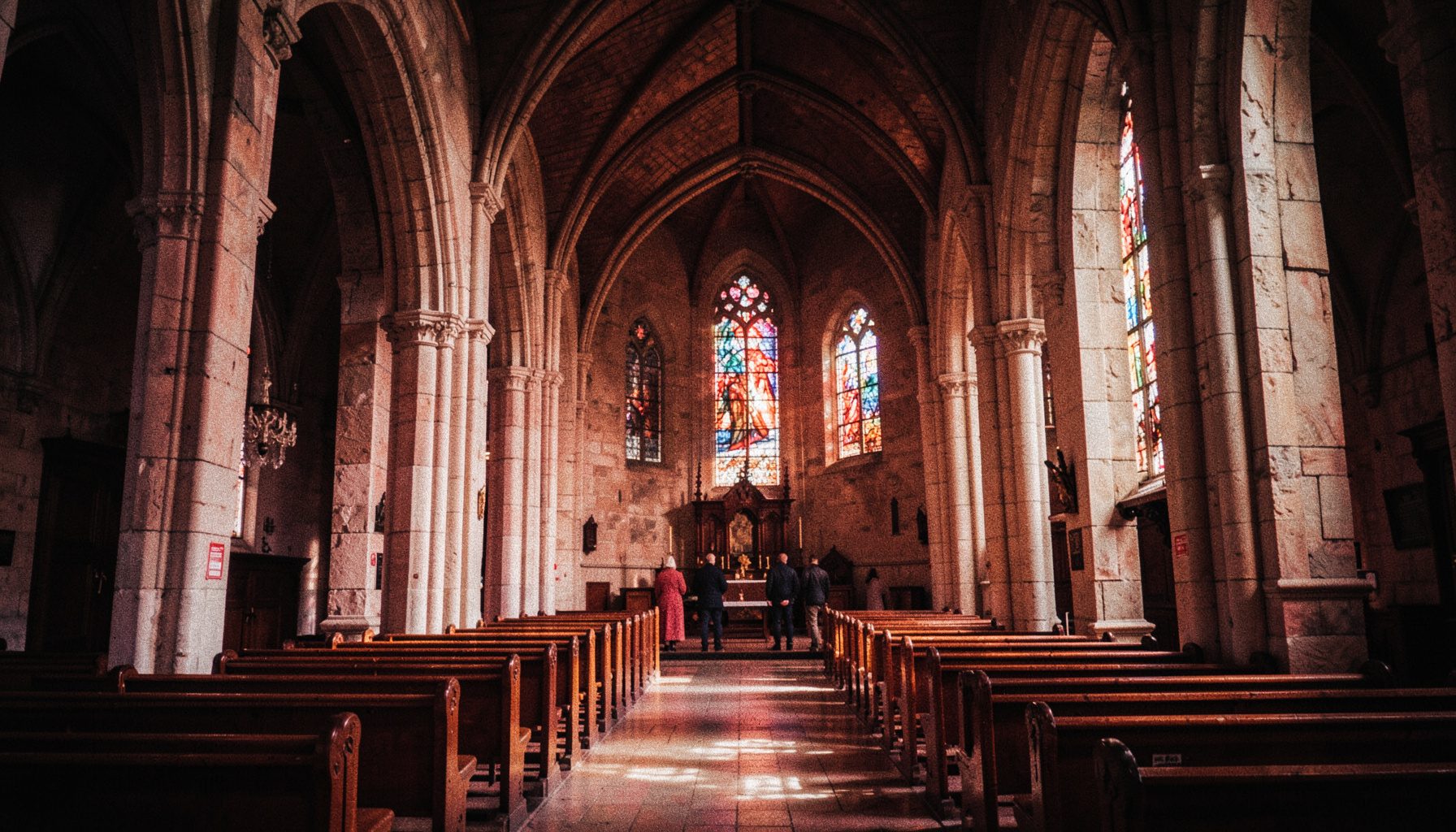 The interior of St Mary's Cathedral with tall stone arches, wooden pews, and stained glass windows glowing in warm light